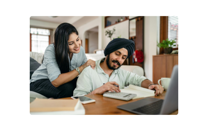 Un couple heureux travaillant sur les finances à la maison avec un ordinateur portable et une calculatrice, explorant des idées de démarrage à faible coût pour le commerce en ligne.